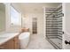Bright bathroom featuring dual vanities, freestanding tub, and glass shower with horizontally striped tile at 8624 Dukes Lake Rd, Zebulon, NC 27597
