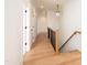 Hallway with hardwood floors, white walls, and staircase with dark railings at 8624 Dukes Lake Rd, Zebulon, NC 27597