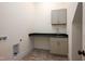 Bright laundry room with gray cabinetry, stainless steel sink, and brick floors at 8624 Dukes Lake Rd, Zebulon, NC 27597