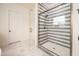 Modern bathroom featuring a glass enclosed shower with bronze hardware and white and gray striped tile at 8624 Dukes Lake Rd, Zebulon, NC 27597