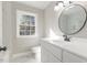 Bright bathroom with a large round mirror, modern vanity, and marble tiled floor and shower at 203 W Stewart St, Coats, NC 27521