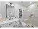 A bathroom with a vanity, black hardware, toilet, tiled walls, and a glass shower stall at 1306 Lennox Pl, Raleigh, NC 27612