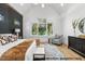 A bedroom with a vaulted ceiling, accent wall, bed, dresser, and view of the outdoors at 1306 Lennox Pl, Raleigh, NC 27612