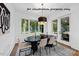 A dining room features a modern light fixture, dining table, and large windows with a view of the outdoors at 1306 Lennox Pl, Raleigh, NC 27612