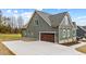 Side exterior view of a home showing the garage, concrete driveway, and manicured landscaping at 25 Basil Ct, Franklinton, NC 27525