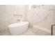 Modern bathroom featuring marble walls, a niche, and a sleek, freestanding bathtub with bronze fixtures at 1226 Red Cedar Ct, Youngsville, NC 27596
