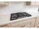 Close-up of the stainless steel stovetop installed on the countertop, with custom cabinets and white backsplash at 1226 Red Cedar Ct, Youngsville, NC 27596
