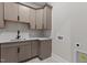 Laundry room with sink and shaker cabinets finished with luxurious countertops and modern black faucet at 30 Hartwood Ln, Youngsville, NC 27596