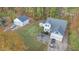 Aerial view of a well-maintained home with a two-car garage, detached garage and brick patio nestled in a wooded setting at 143 Rawhide Dr, Louisburg, NC 27549