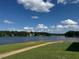 Beautiful lake view with lush greenery, clear blue water, and scattered clouds at 143 Rawhide Dr, Louisburg, NC 27549
