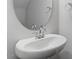 Close-up of a pedestal sink with a circular mirror and chrome fixtures in a modern, minimalist bathroom at 276 White Oak Garden Way # 210, Garner, NC 27529
