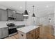 Bright, modern kitchen with stainless appliances, white countertops, light wood flooring and pendant lights above a center island at 276 White Oak Garden Way # 210, Garner, NC 27529