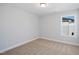 A standard bedroom featuring neutral carpet and a window with a view of the adjacent house at 604 Spellbrook Rd, Zebulon, NC 27597