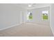 Bright bedroom features neutral walls, plush carpet, ceiling fan, and windows with neighborhood views at 604 Spellbrook Rd, Zebulon, NC 27597
