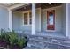 Inviting front porch with stone steps, decorative columns, and a freshly painted door at 1112 Armsleigh Ct, Raleigh, NC 27603