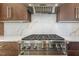 Close up of Wolf stainless steel range and hood featuring quartz backsplash and custom wood cabinets at 196 Mountaintop Cir, Pittsboro, NC 27312
