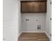 Bright laundry room with wooden cabinets and wood-look flooring at 255 Chesapeake Commons St # 90, Garner, NC 27529