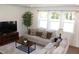 This is a bright living room featuring a beige sofa, wooden furniture, an area rug, and a large window for natural light at 316 Robert Howe Dr, Fuquay Varina, NC 27526
