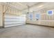 A spacious garage features a white garage door, concrete floor, and natural light from the windows at 87 Browning Mill Dr, Wendell, NC 27591