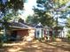 Beautiful brick home with a carport and inviting entrance with white pillars, nestled under mature trees for added curb appeal at 6349 Elevation Rd, Benson, NC 27504