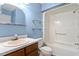 Bathroom featuring blue walls, white vanity, and tub/shower combo with glass shelves at 14 Stone Village Ct, Durham, NC 27704