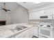 Bright kitchen featuring white appliances, cabinets, and countertops overlooking a living area with vaulted ceiling and fireplace at 14 Stone Village Ct, Durham, NC 27704