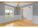 Light-filled dining room with wainscoting, a chandelier, and a view of the front yard through large windows at 20 Water Willow Ln, Zebulon, NC 27597