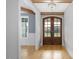 Elegant entryway with wooden beams, chandelier, and arched glass paneled double doors at 20 Water Willow Ln, Zebulon, NC 27597