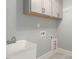 Convenient laundry room with white cabinets, utility sink, washer/dryer hookups, and tiled flooring at 20 Water Willow Ln, Zebulon, NC 27597