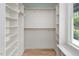 Spacious walk-in closet with wooden shelving, hardwood flooring and natural light from adjacent window at 20 Water Willow Ln, Zebulon, NC 27597