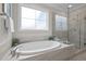 Bright bathroom featuring a soaking tub, walk-in shower, and a large window for natural light at 181 Colonial Ridge Dr, Pittsboro, NC 27312
