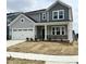 Charming two-story home featuring a welcoming front porch with stone accents and stylish gray siding at 657 Sun Meadow Dr, Wake Forest, NC 27587