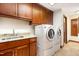 Well-organized laundry room with wooden cabinets, granite counters, and modern washer/dryer at 106 Springbrook Pl, Cary, NC 27518