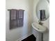 Bathroom featuring a pedestal sink, round mirror, and towel rack with soft gray towels at 120 Parker Ln, Mebane, NC 27302