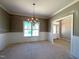 Dining room features modern chandelier, wainscoting, window with natural light, and entry to foyer at 1665 S Old Carriage Rd, Rocky Mount, NC 27804