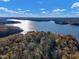 Scenic aerial shot showcasing a tranquil lake surrounded by vibrant fall foliage and blue sky at 3217 Satterwhite Point Rd, Henderson, NC 27537