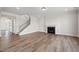Bright living room with hardwood floors, fireplace, and staircase with decorative metal spindles at 1233 Cricket St, Elon, NC 27244