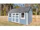 Light blue storage shed features double doors and windows providing secure storage and natural light at 34 Mcintosh Ct, Fuquay Varina, NC 27526