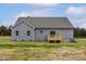 View of the back of a house with gray siding and a small, wooden deck and grassy yard at 11376 International Dr, Middlesex, NC 27557