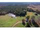 Extensive aerial shot displaying a home by a serene pond, bordered by flourishing forests and sweeping meadows at 206 Pike Memory Ln, Staley, NC 27355