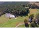 Expansive aerial image capturing a residence by a shimmering pond, nestled in a vast landscape of forests and fields at 206 Pike Memory Ln, Staley, NC 27355