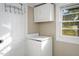 Functional laundry room with overhead storage and a bright window, providing a practical space at 206 Pike Memory Ln, Staley, NC 27355