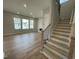 Open-concept living room features wood floors, bright windows, and staircase at 409 Marthas View Way, Wake Forest, NC 27587