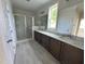 Bathroom featuring double sink vanity, marble counters, and glass enclosed shower at 6044 Scalybark Road, Durham, NC 27712