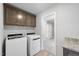 Well-organized laundry room featuring modern machines, overhead cabinets, and a granite countertop at 77 Buckhorn Branch Park # 174, Clayton, NC 27520