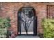 Arched brick entryway with decorative iron gate featuring a tree design, providing secure access to the property at 807 W Trinity Ave # 220, Durham, NC 27701