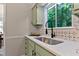 A kitchen sink with a forest view, light green cabinets, and a modern faucet and countertop at 2704 Ross Rd, Durham, NC 27703