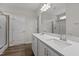Modern bathroom featuring a double vanity with white countertops and cabinets, complemented by wood-look flooring and a glass-enclosed shower at 585 Husketh Rd, Youngsville, NC 27596