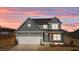 Charming two-story home featuring gray siding, a two-car garage, and a welcoming teal front door at 585 Husketh Rd, Youngsville, NC 27596