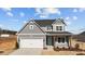 Charming two-story home featuring gray siding, a two-car garage, and a welcoming teal front door at 585 Husketh Rd, Youngsville, NC 27596